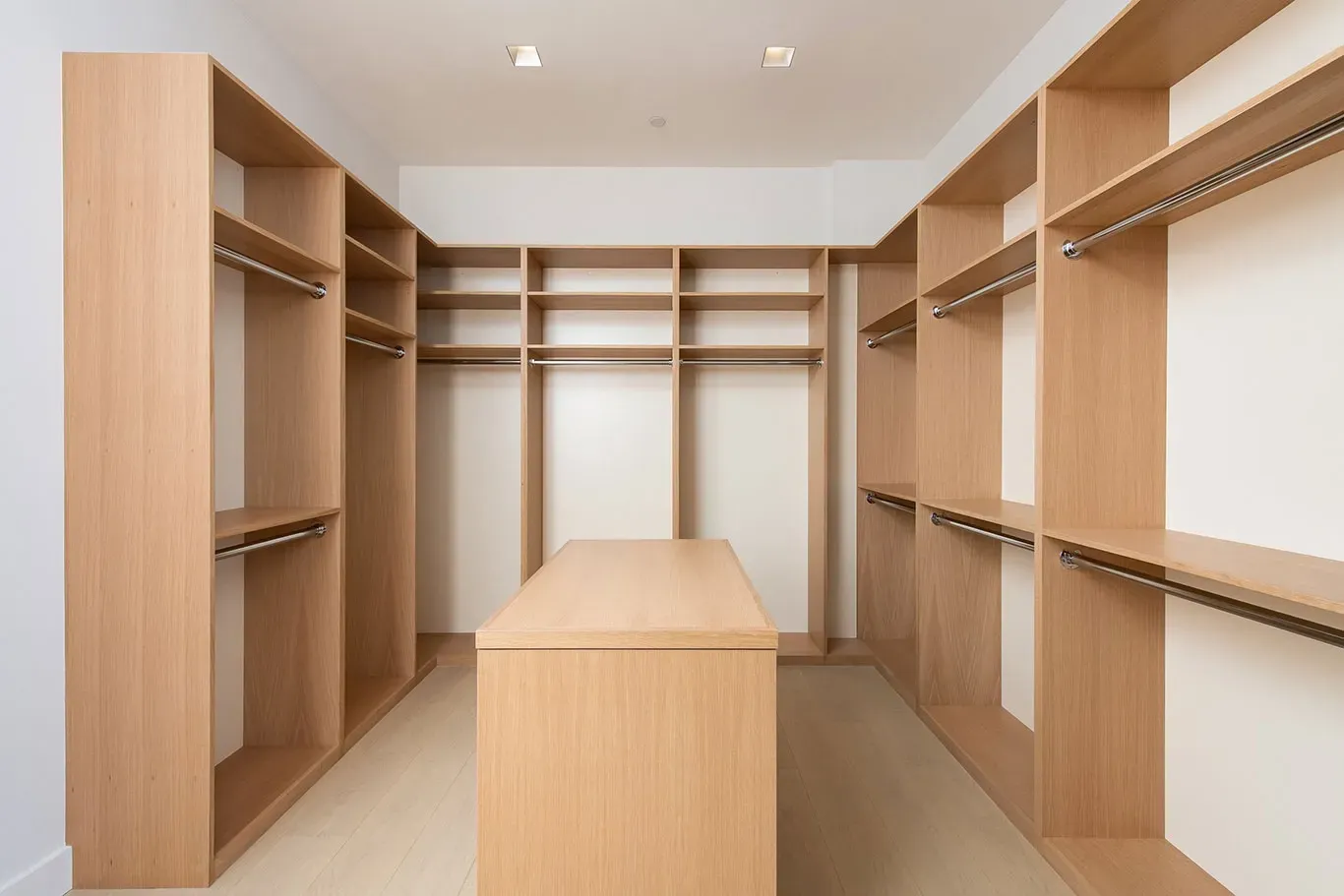 An empty walk in closet with wooden shelves and clothes racks.