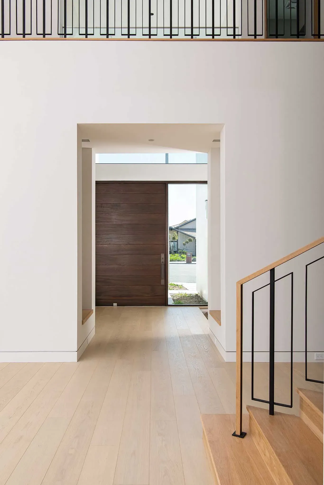 A hallway with a wooden door and stairs in a house.