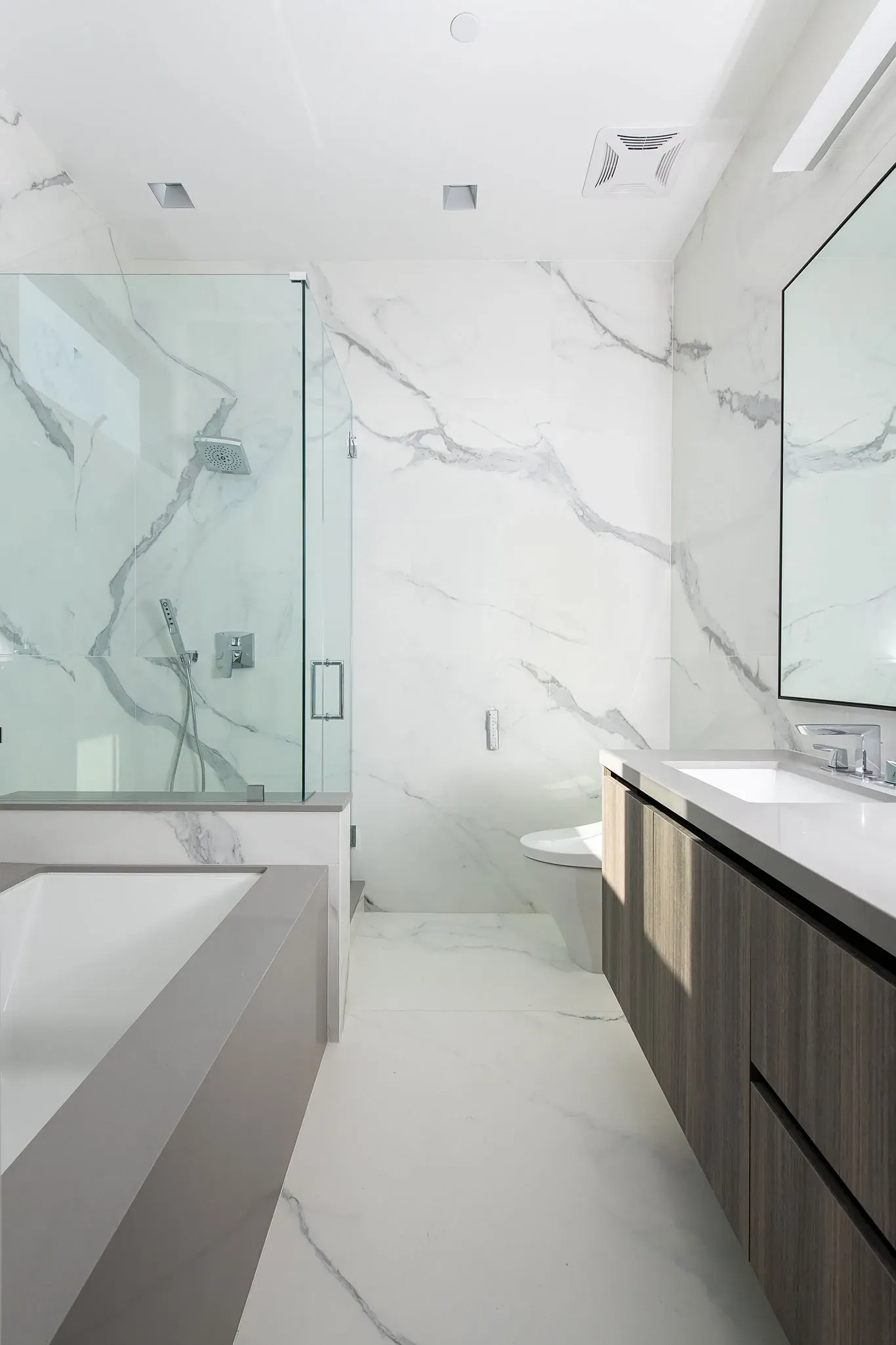 A bathroom with a tub , sink , mirror and shower.