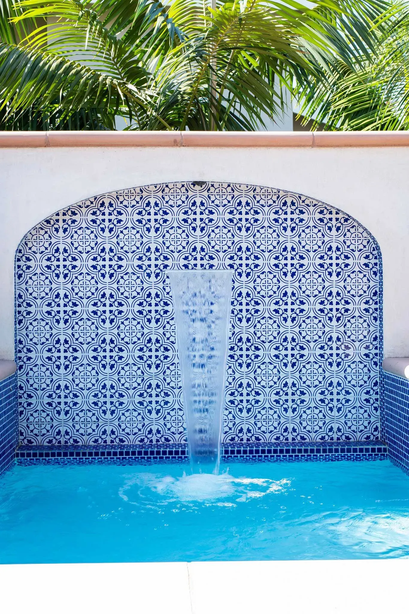 There is a waterfall in the middle of a swimming pool.
