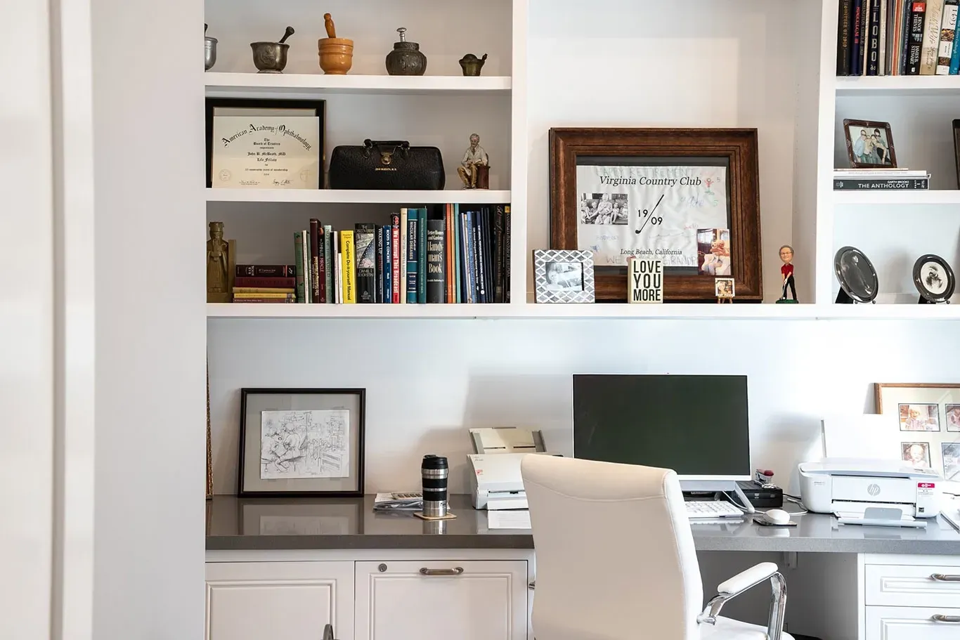 A home office with a desk , chair , computer and bookshelves.
