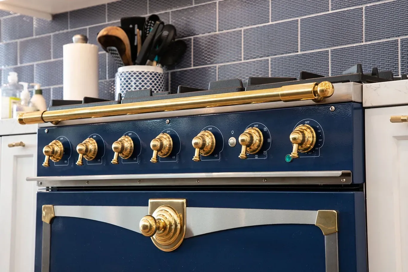 A blue stove with gold knobs is in a kitchen.