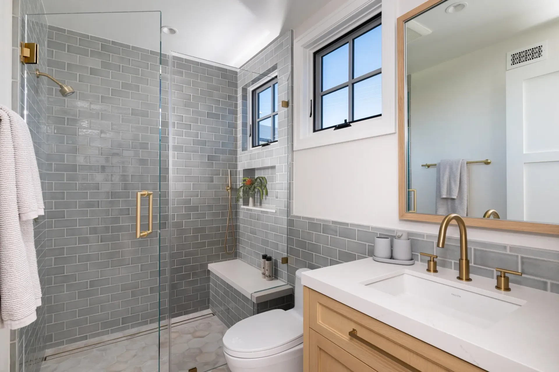 A bathroom with a toilet , sink , mirror and walk in shower.