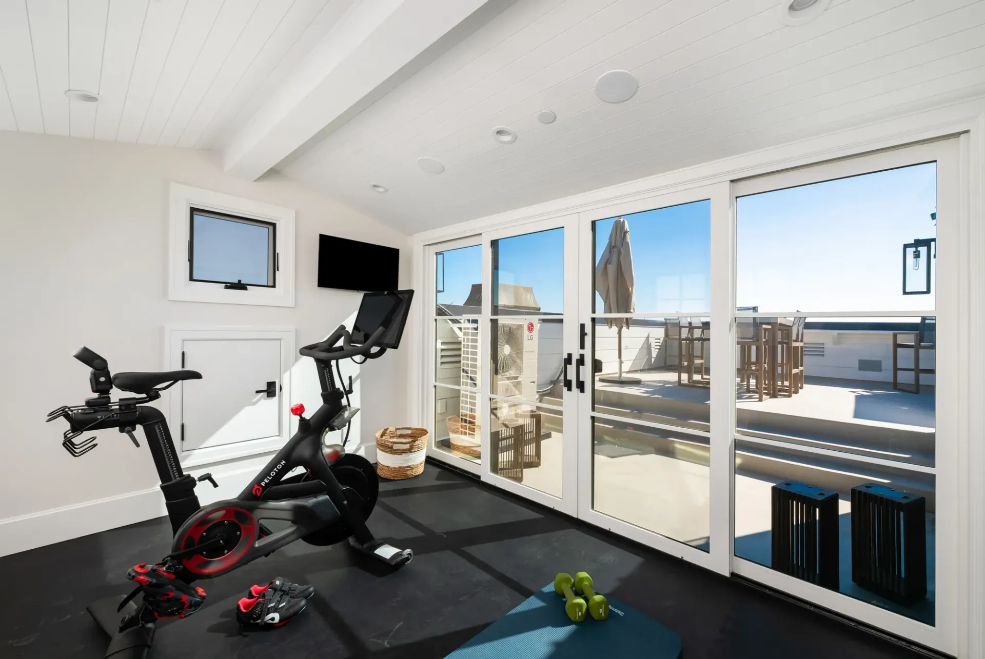 A home gym with a peloton bike and a television.
