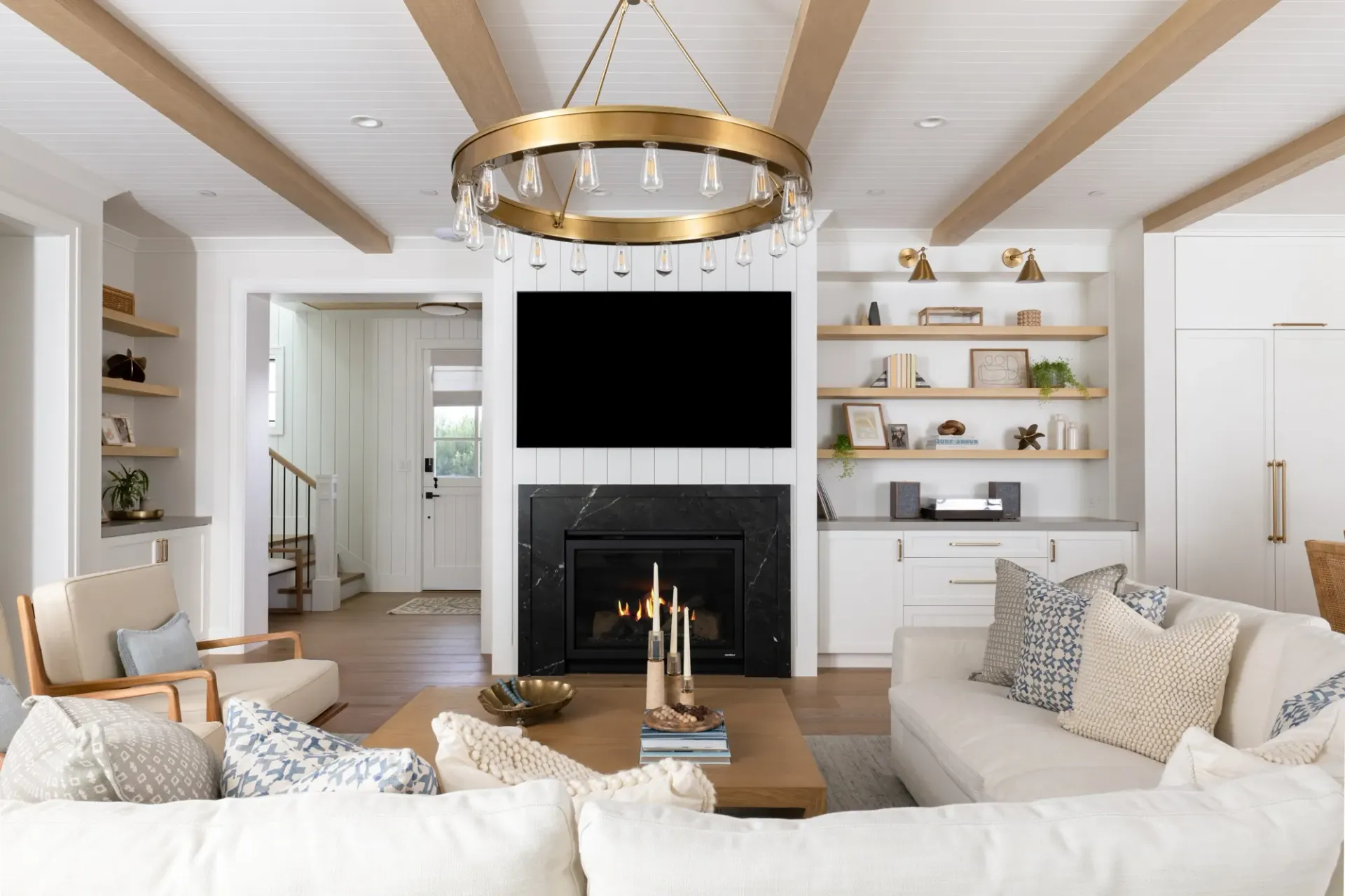 A living room with a couch , fireplace , television and chandelier.