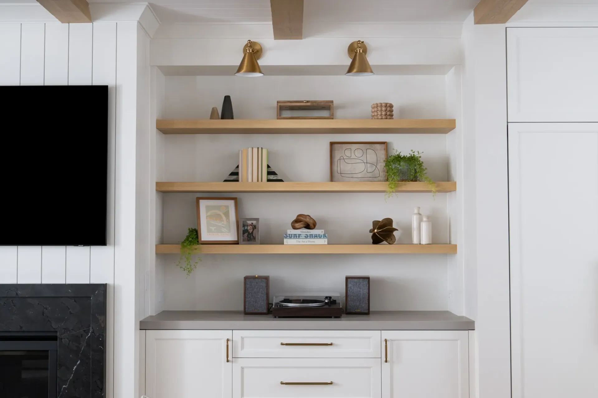 A living room with a fireplace , shelves , and a flat screen tv.
