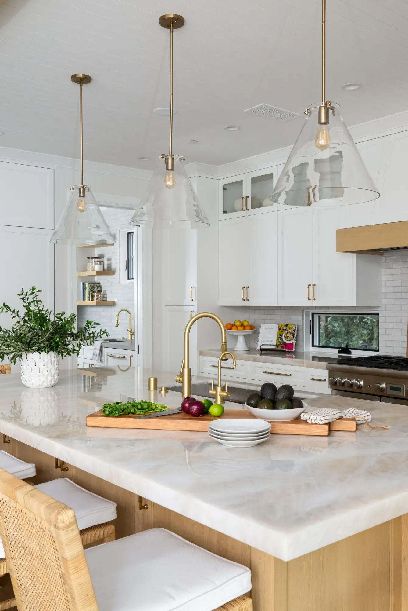 A kitchen with white cabinets , a large island , a sink , and a stove.