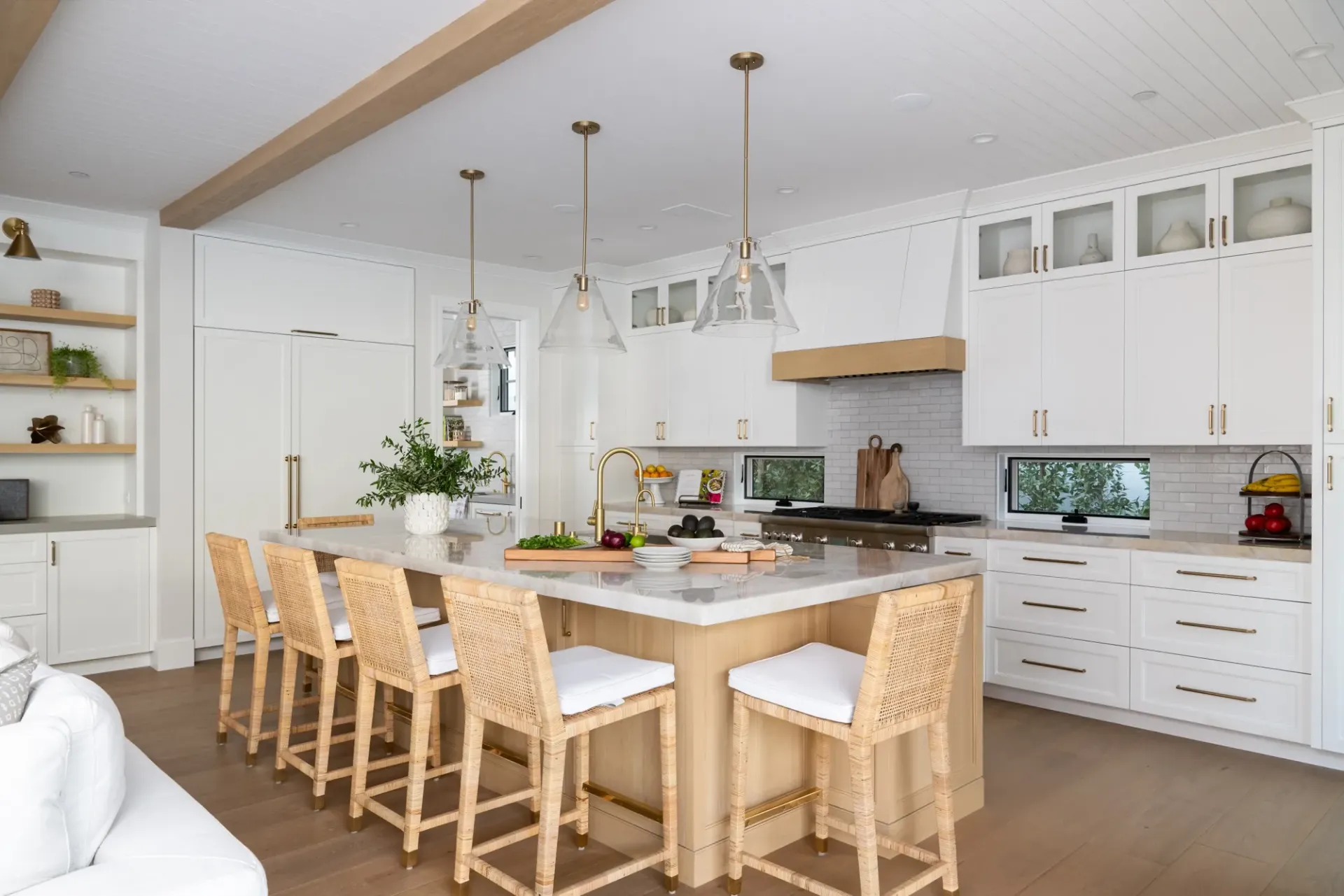 A kitchen with white cabinets , a large island , and wicker chairs.