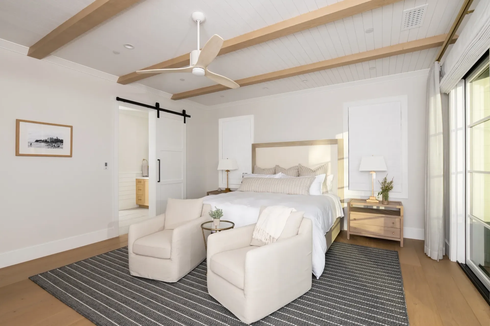 A bedroom with a large bed , two chairs and a ceiling fan.