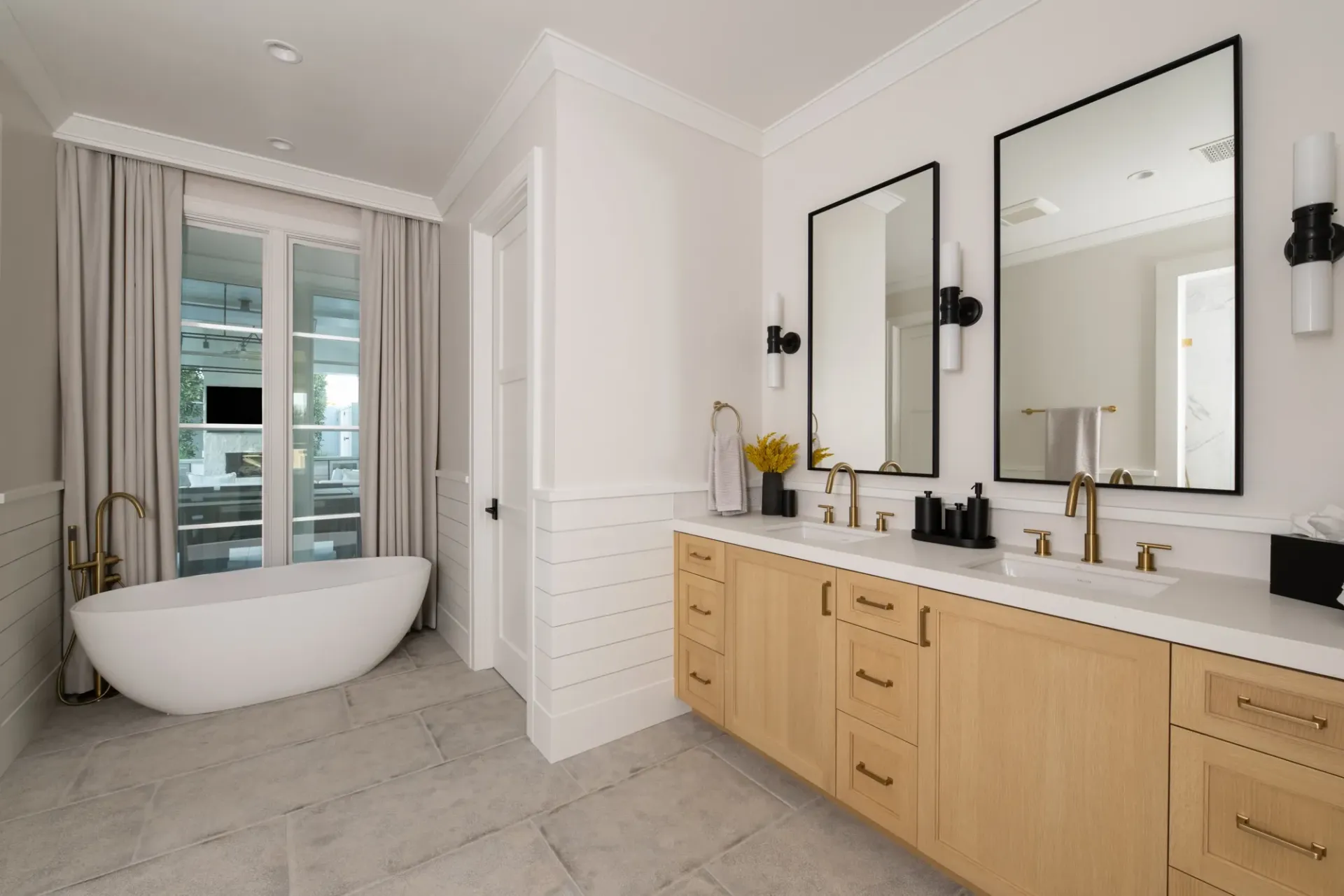 A bathroom with two sinks , a tub , and two mirrors.