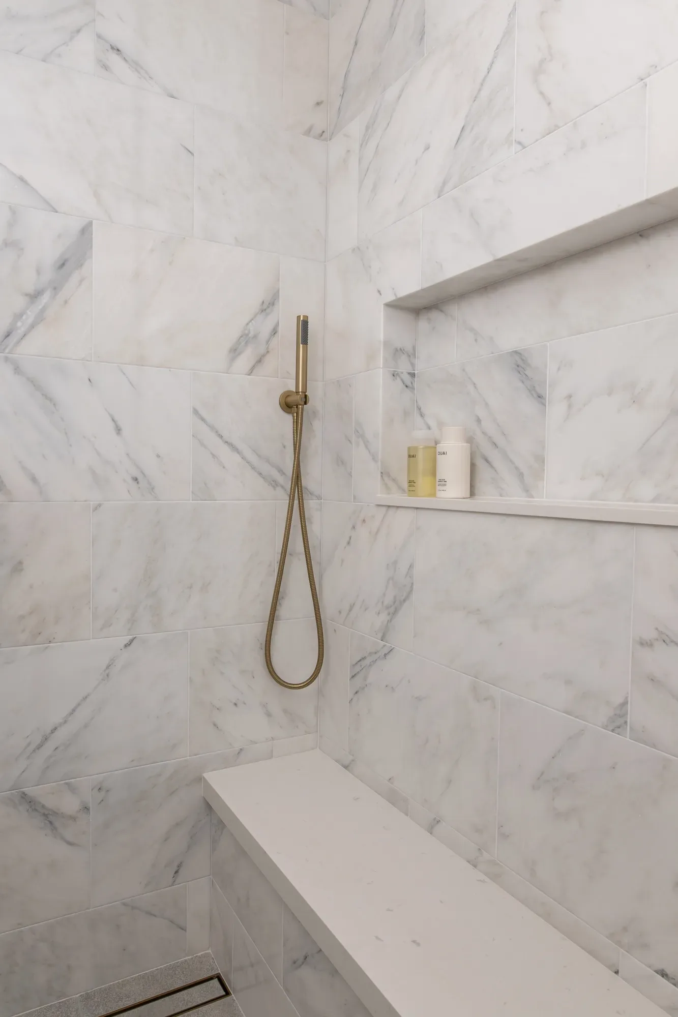 A shower with a bench and a shower head in a bathroom.