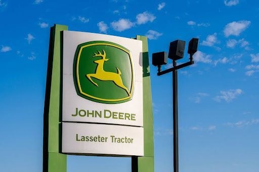 A John Deere Lasseter Tractor dealership sign with a deer on it.