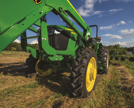 A green and yellow John Deere utility tractor is parked in a field