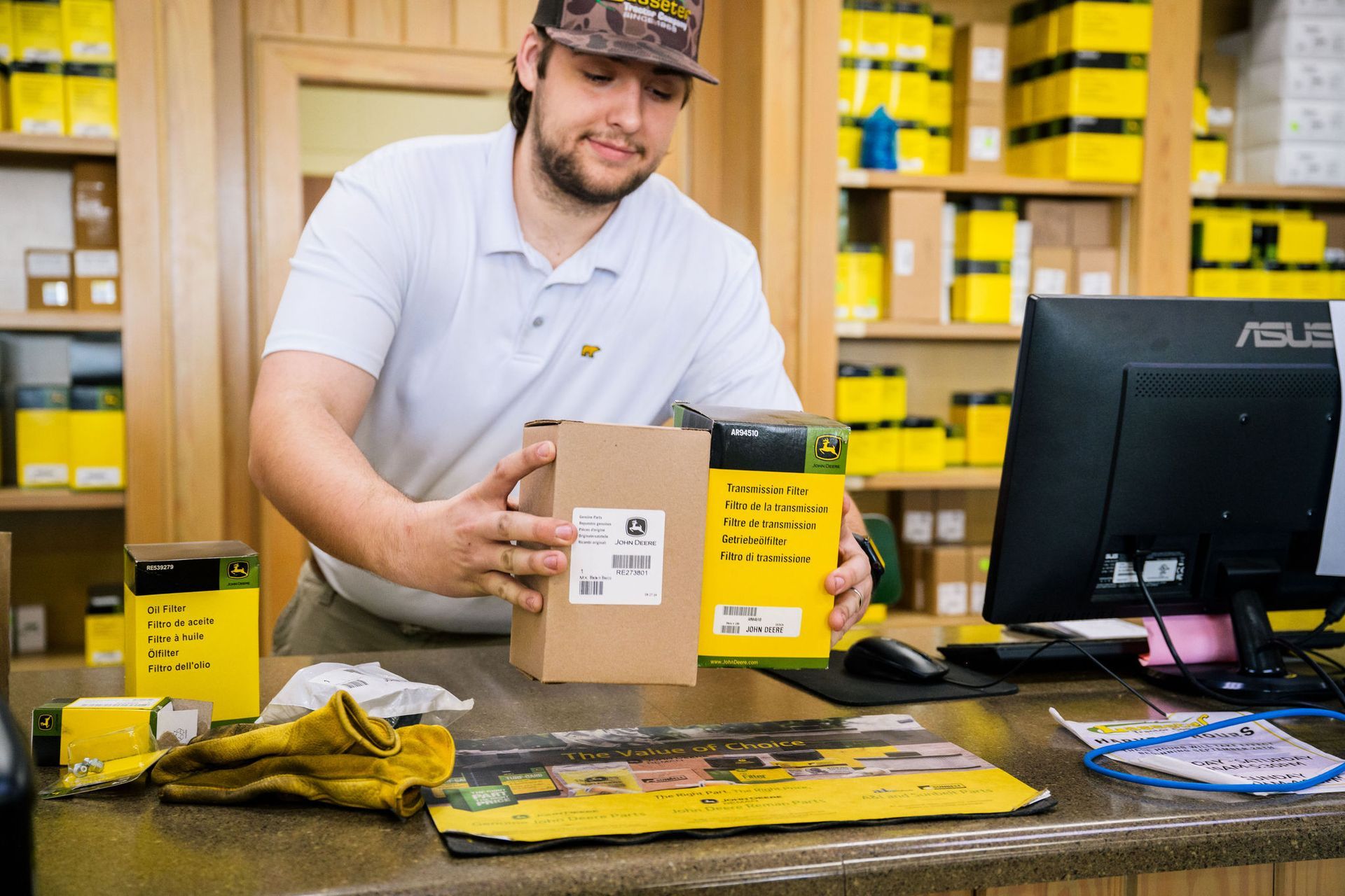 A man is holding a box in front of a computer in a store.