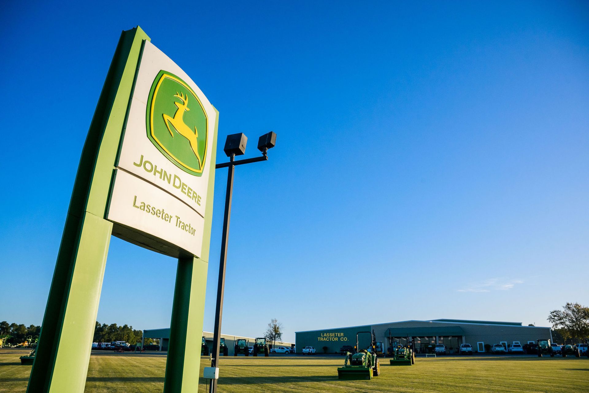 A John Deere Lasseter Tractor dealership sign with a deer on it.