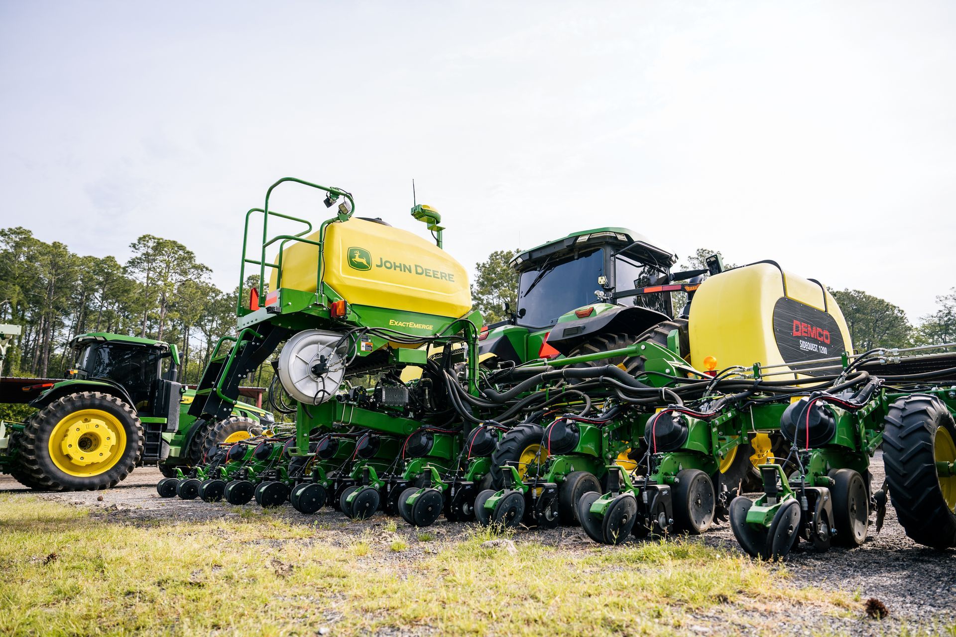 A john deere planter is parked next to a tractor in a field.
