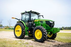 A green and yellow John Deere tractor is parked in a field.