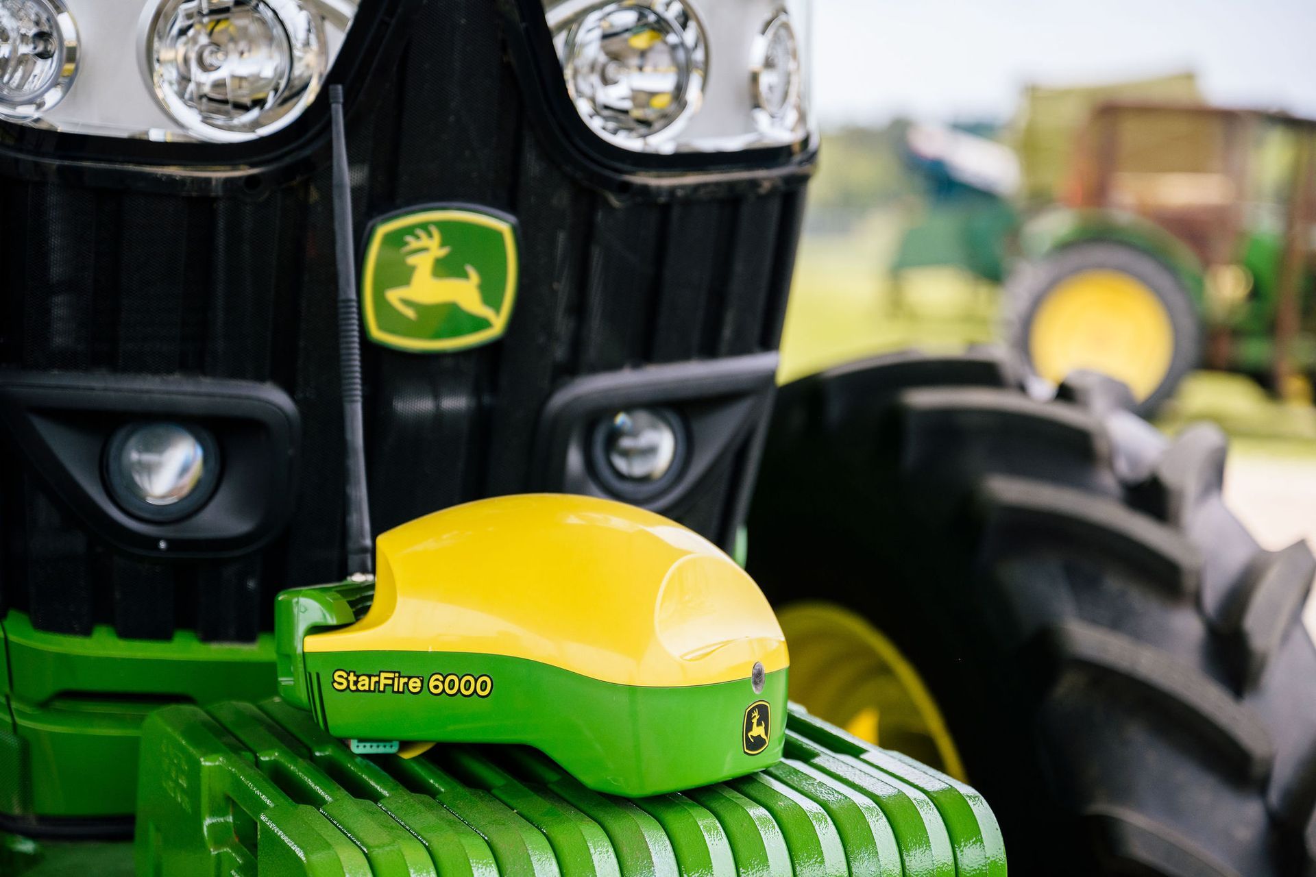 A green and yellow john deere tractor with a yellow device on the front.