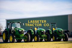 A row of green and yellow John Deere tractors are parked next to each other.