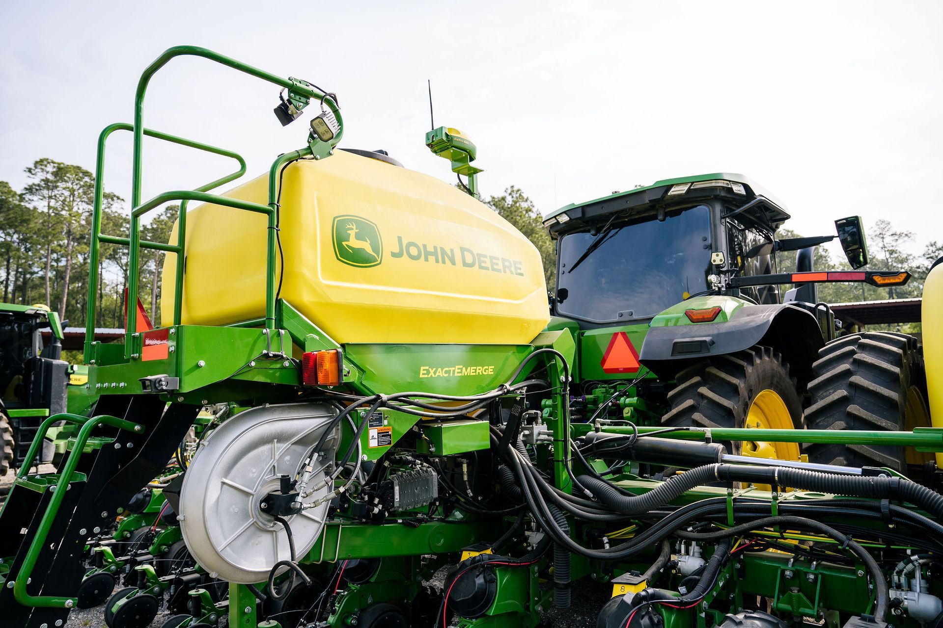 A john deere tractor is parked next to a john deere planter.