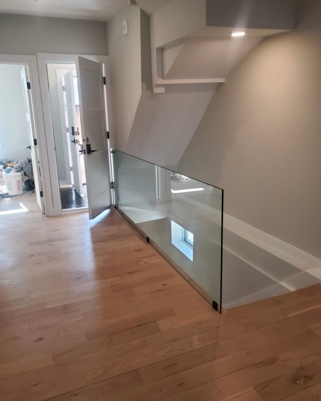 A staircase with a glass railing and wooden floors in a house.