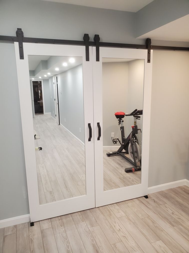A sliding barn door with a mirror and a bicycle in the background.