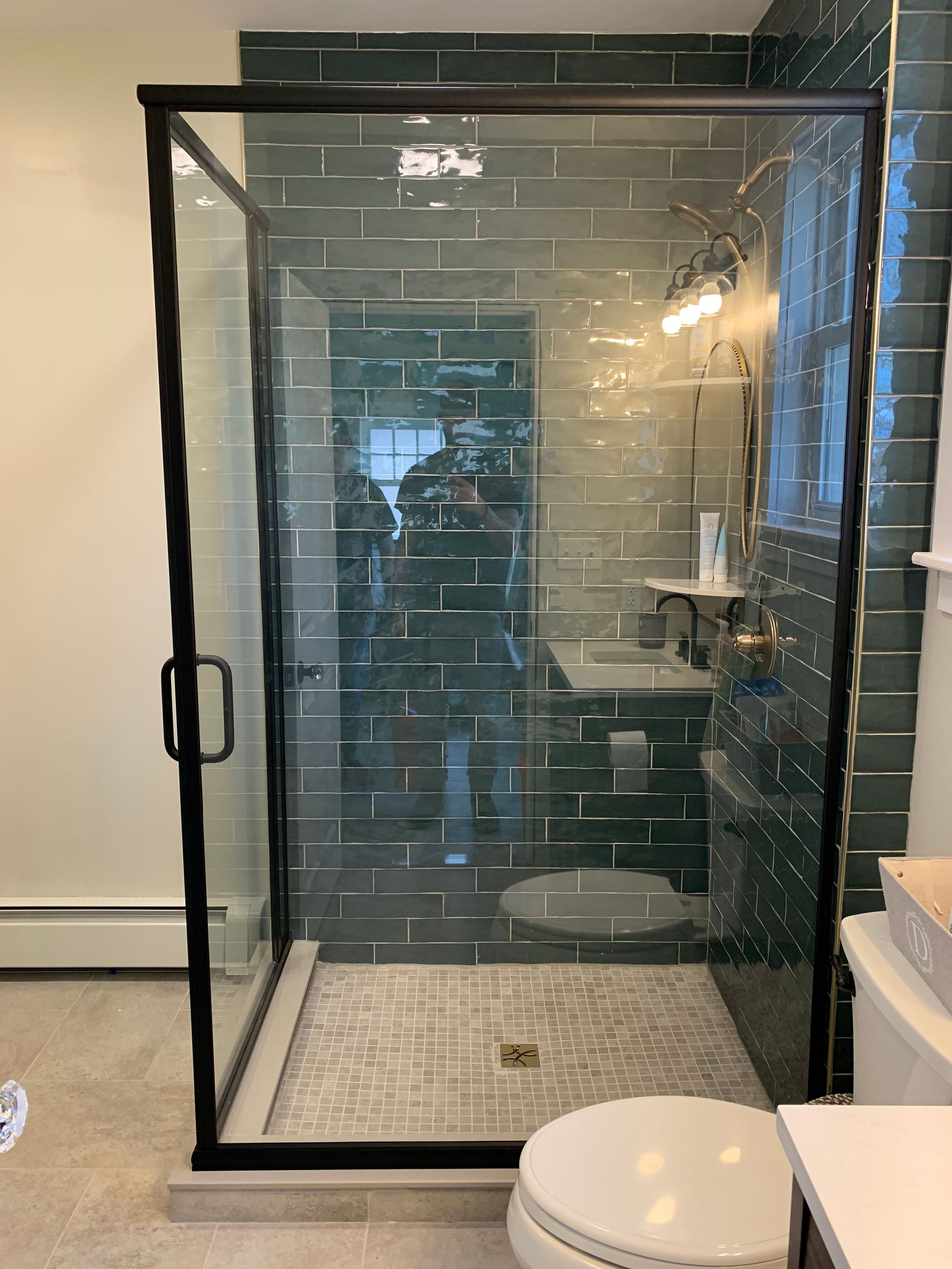 A bathroom with a walk in shower , toilet , sink and mirror.