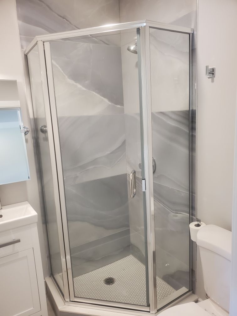 A bathroom with a shower stall , toilet , sink and mirror.