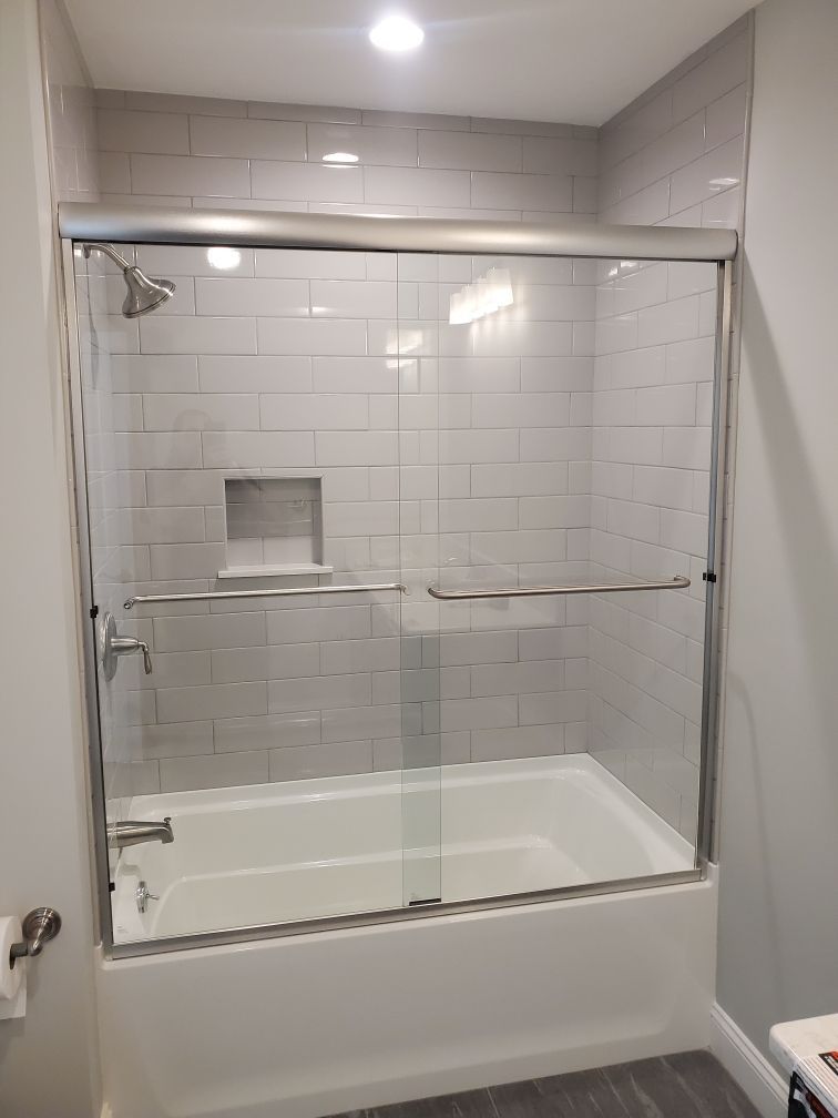 A bathroom with a bathtub and a shower with a sliding glass door.