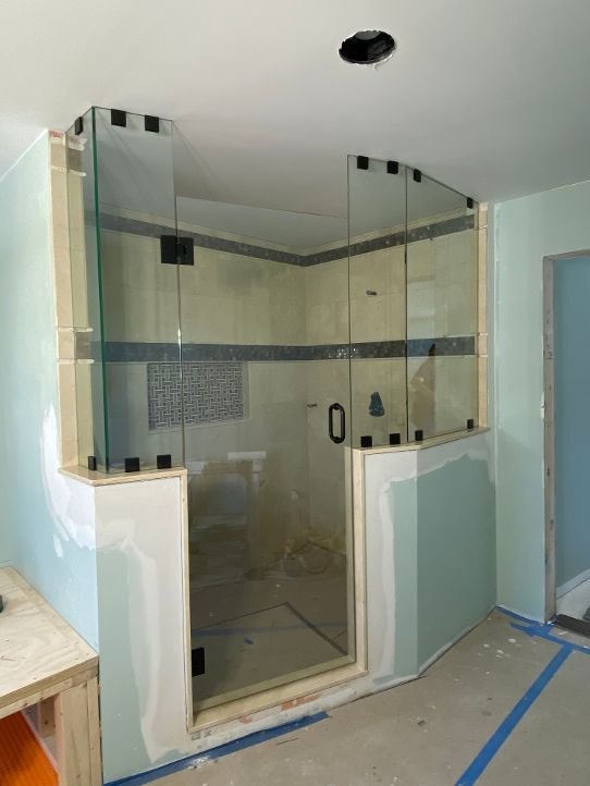 A bathroom under construction with a glass shower door.