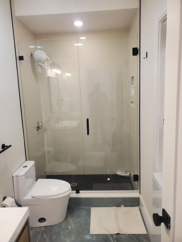 A bathroom with a toilet , sink and shower with a glass door.