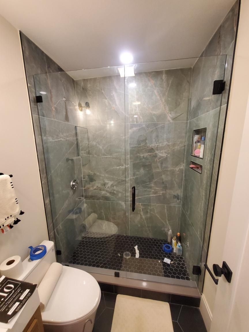 A bathroom with a toilet and a shower with a glass door.