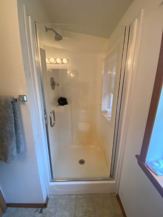 A bathroom with a walk in shower and a window.