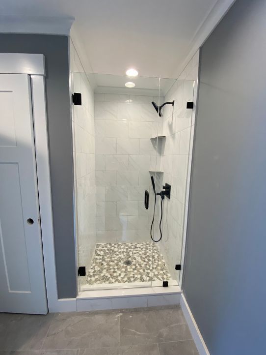A bathroom with a walk in shower with a glass door.
