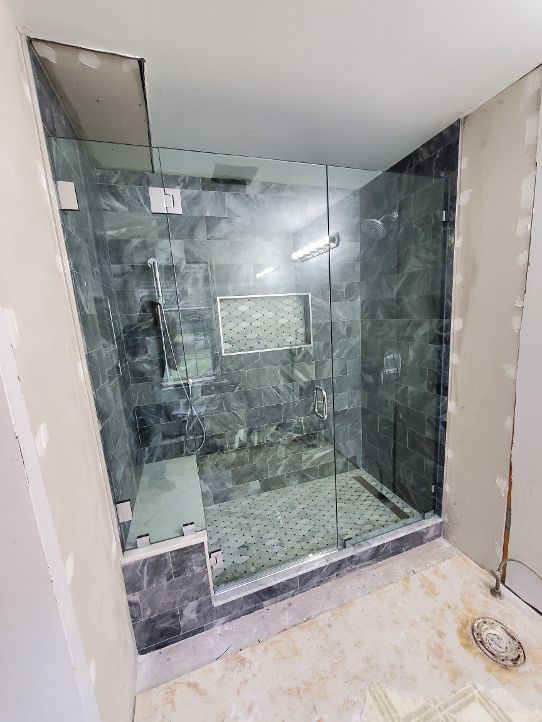 A bathroom with a walk in shower with a glass door.