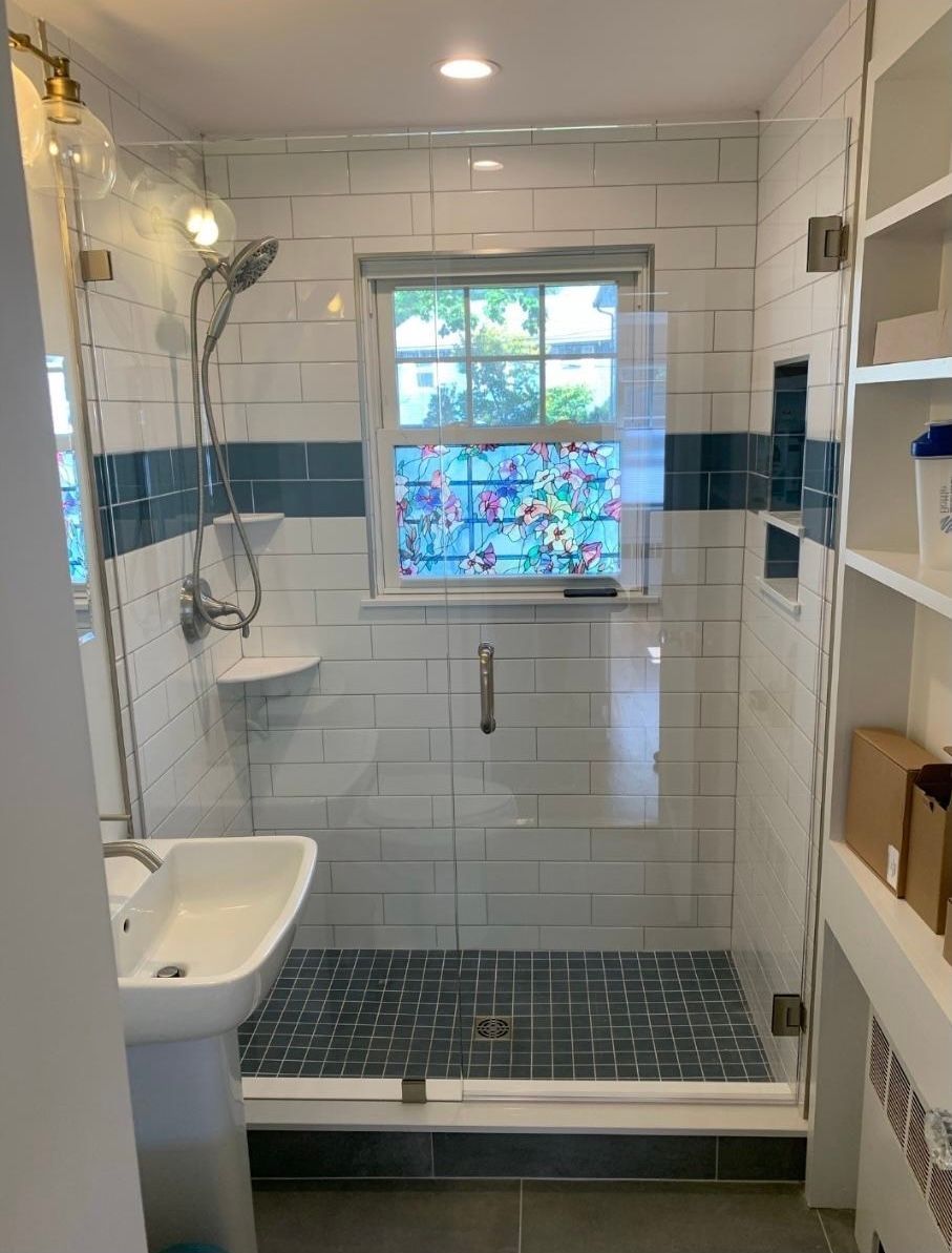 A bathroom with a shower , sink , and window