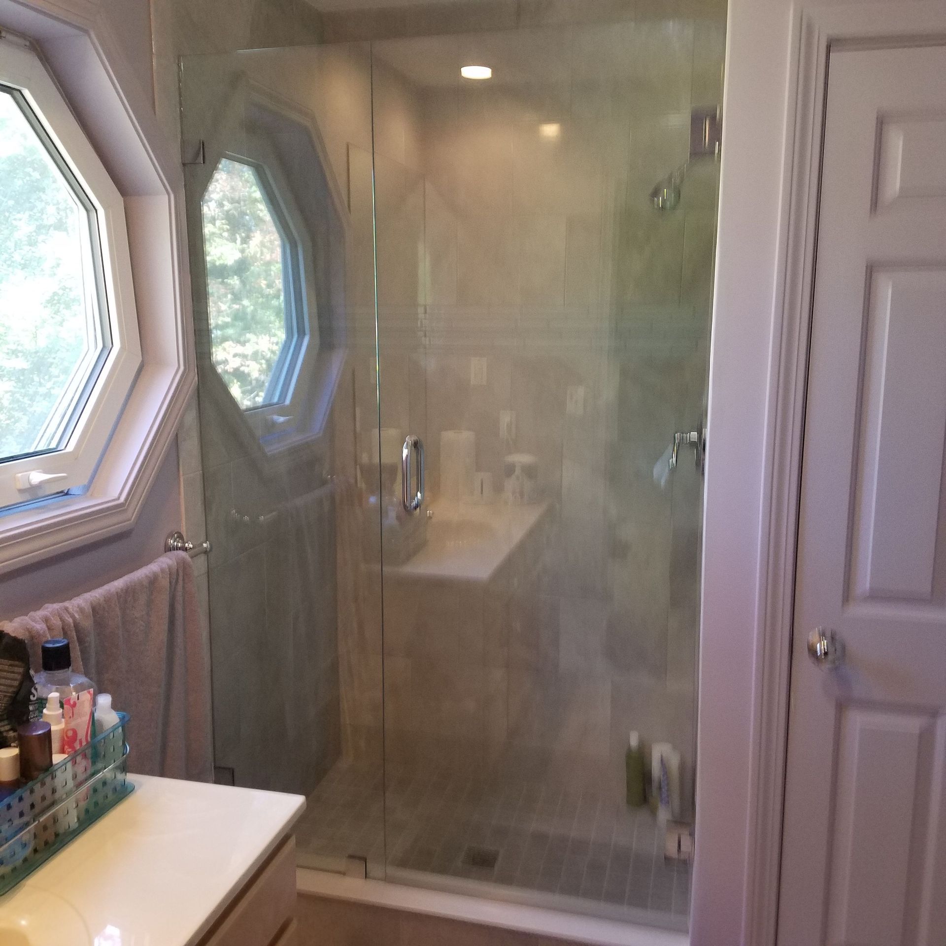 A bathroom with a walk in shower and a window
