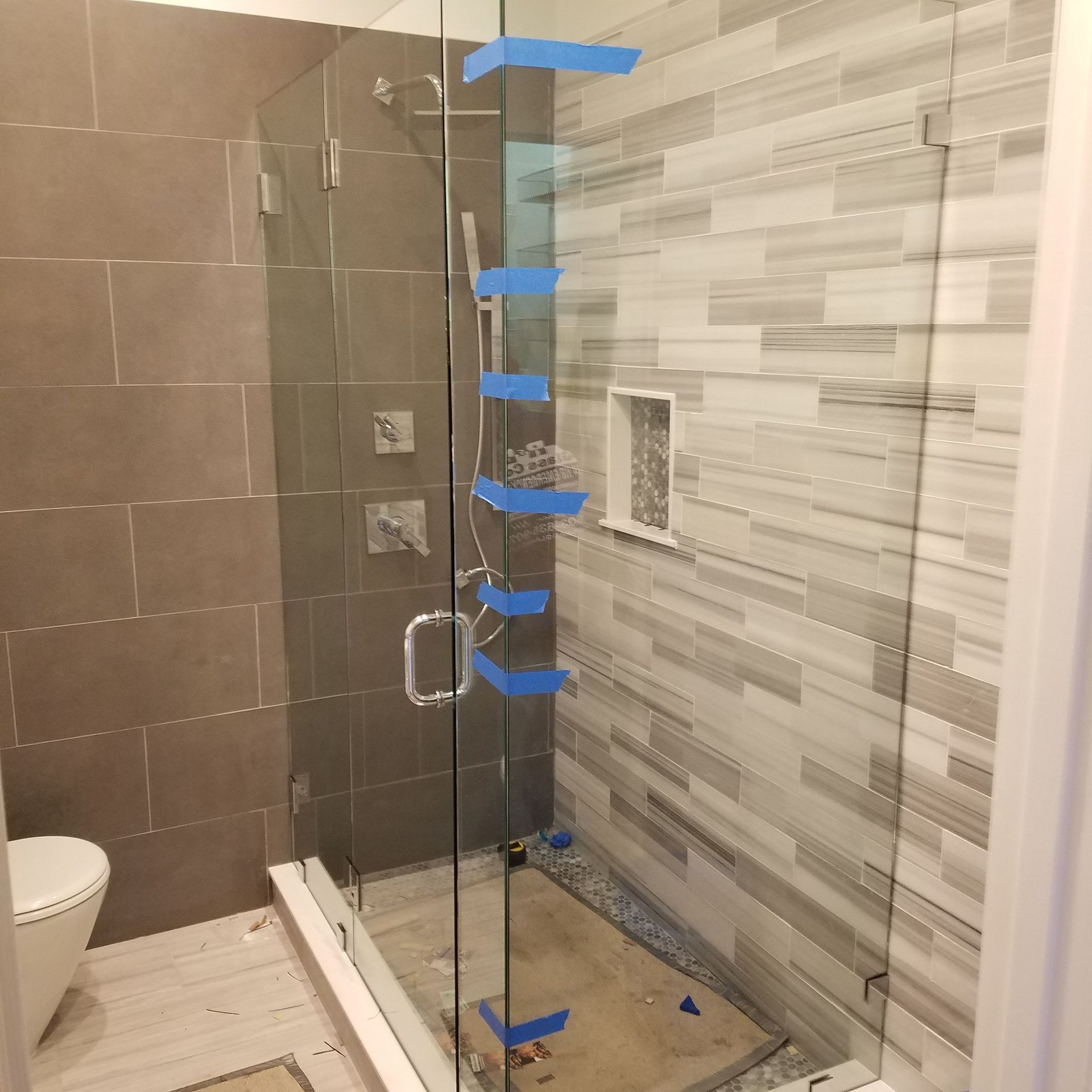 A bathroom with a glass shower door and a toilet.