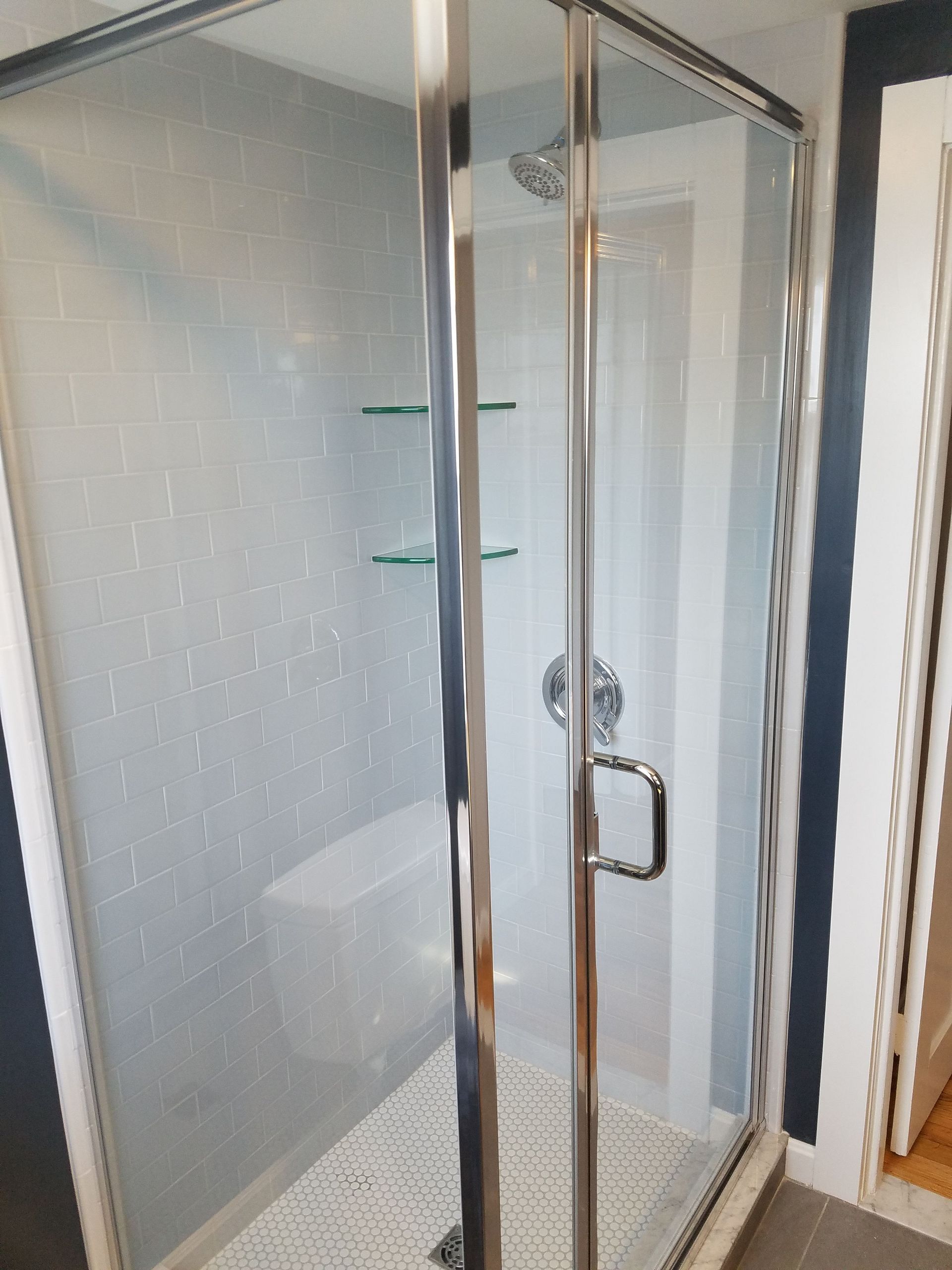 A bathroom with a walk in shower with a glass door.