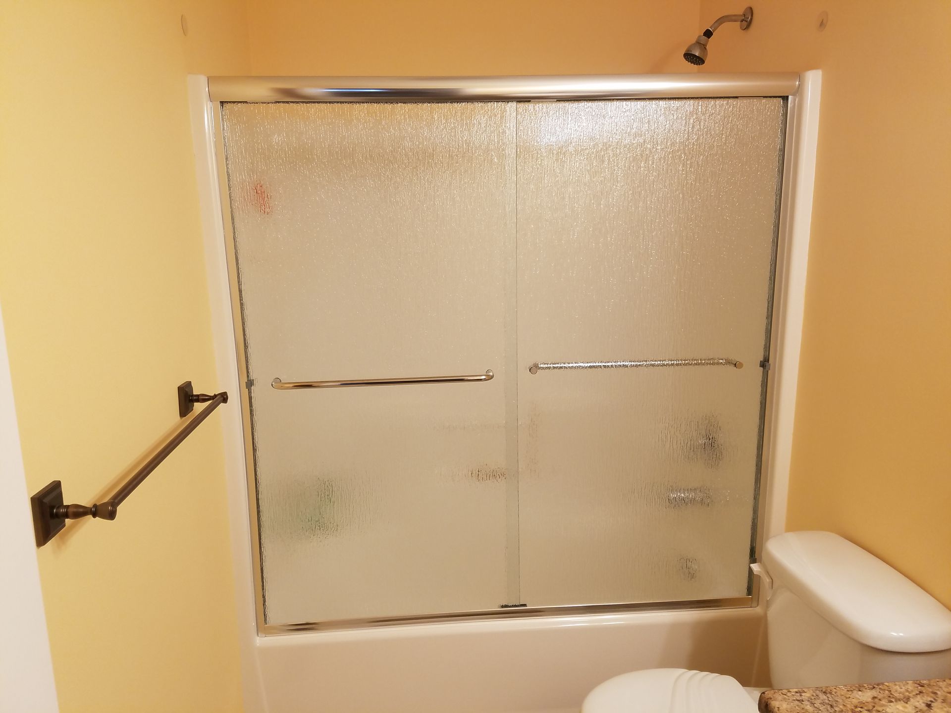 A bathroom with a sliding glass shower door