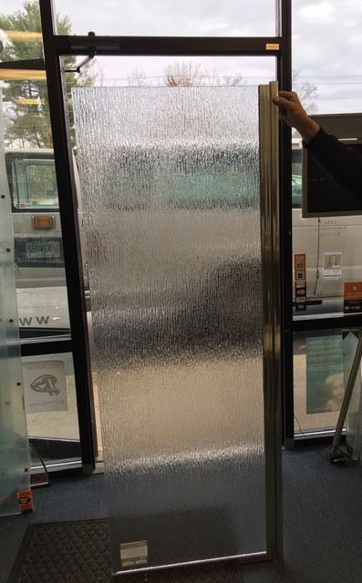 A person is holding a piece of glass in front of a window.