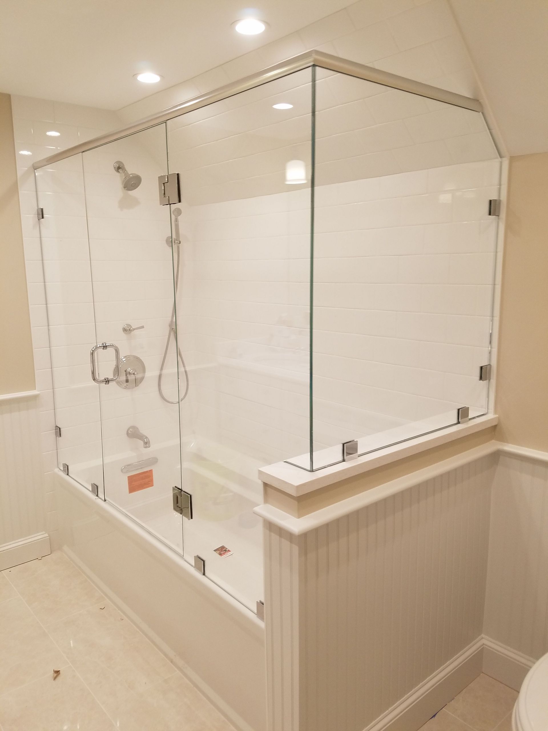 A bathroom with a bathtub and a toilet with a glass shower door