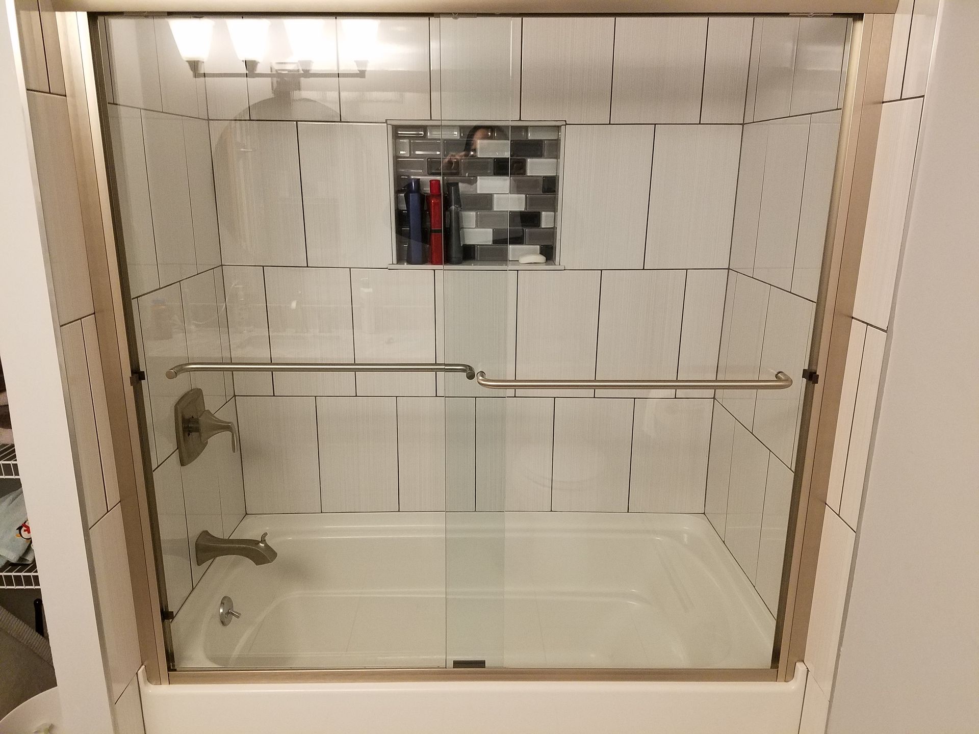 There is a bathtub in the shower with a glass door.