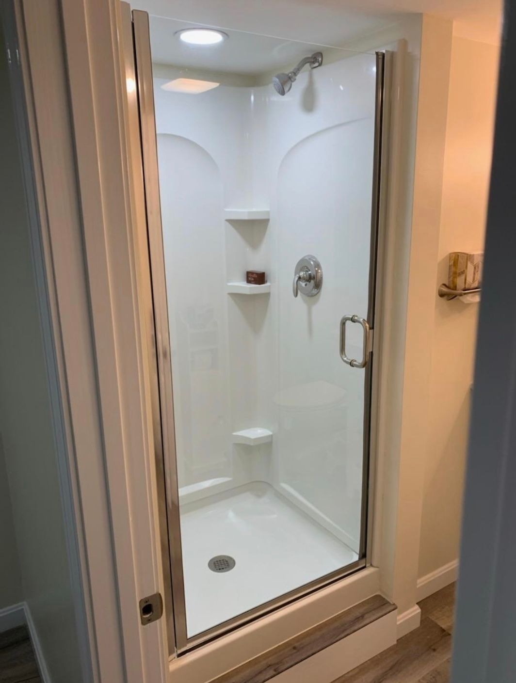 A bathroom with a walk in shower with a glass door.