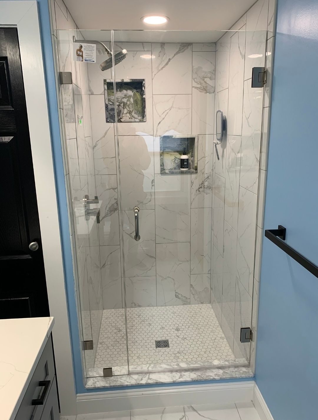 A bathroom with a walk in shower with a glass door.