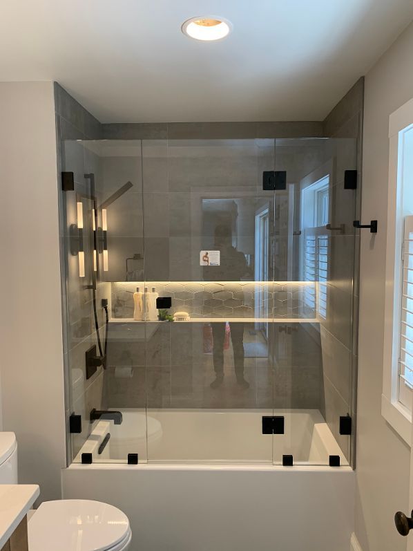 A bathroom with a bathtub , toilet , shower and glass shower door.