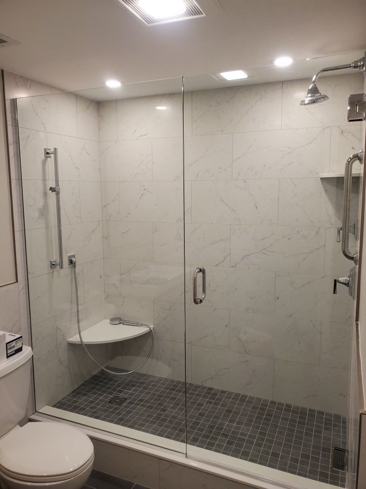 A bathroom with a toilet and a walk in shower with a glass door.