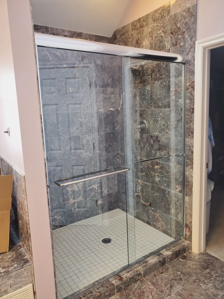 A bathroom with a walk in shower with a sliding glass door.