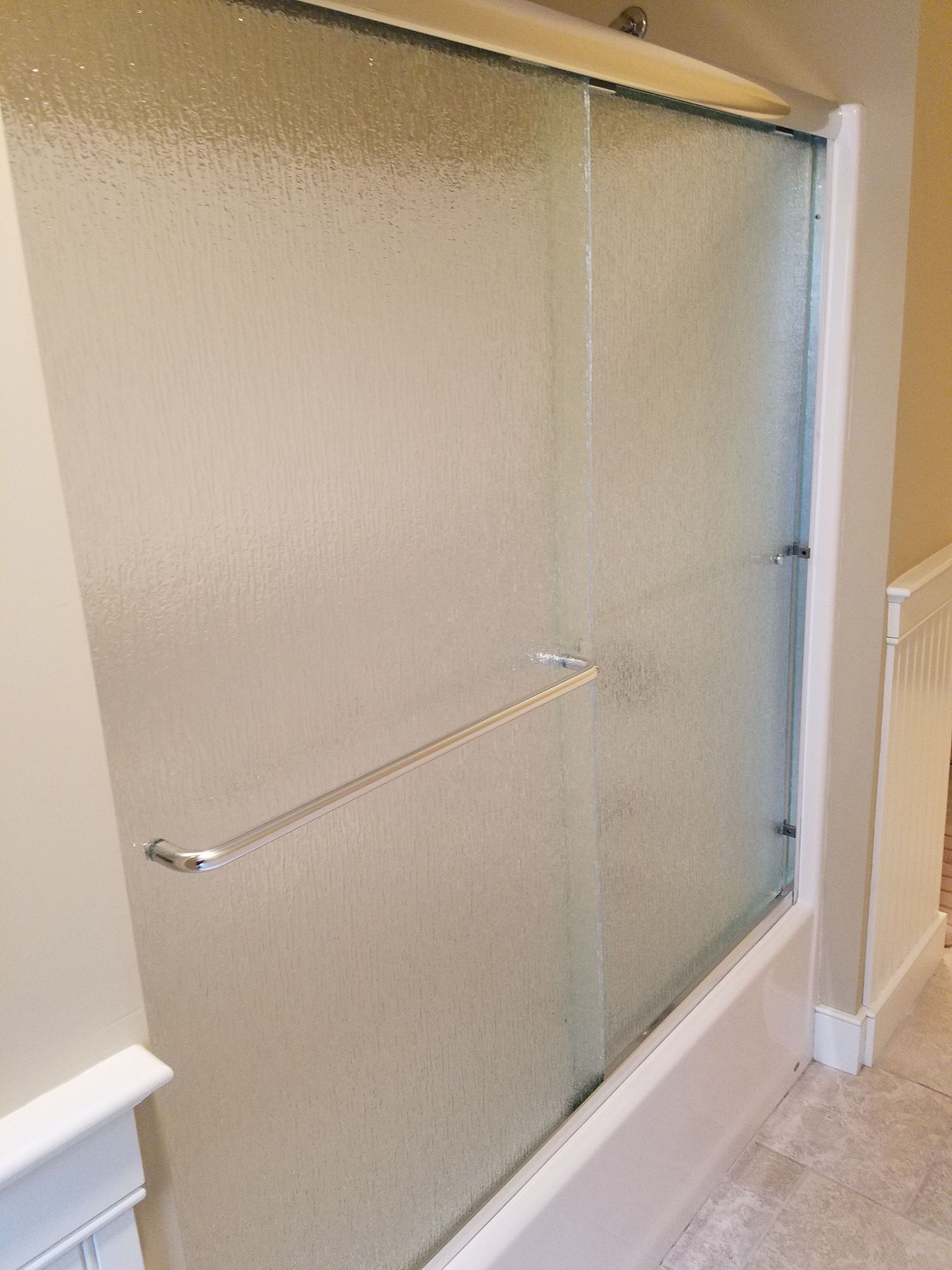 A bathroom with a sliding glass shower door and a bathtub.
