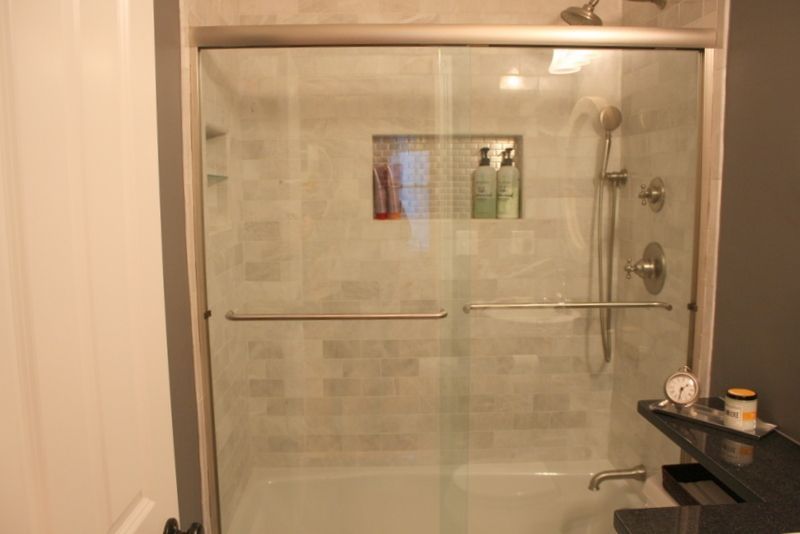 A bathroom with a sliding glass shower door and a bathtub.